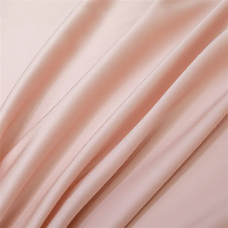 A close-up of a flowing, silky pink bamboo flat sheet draped softly.