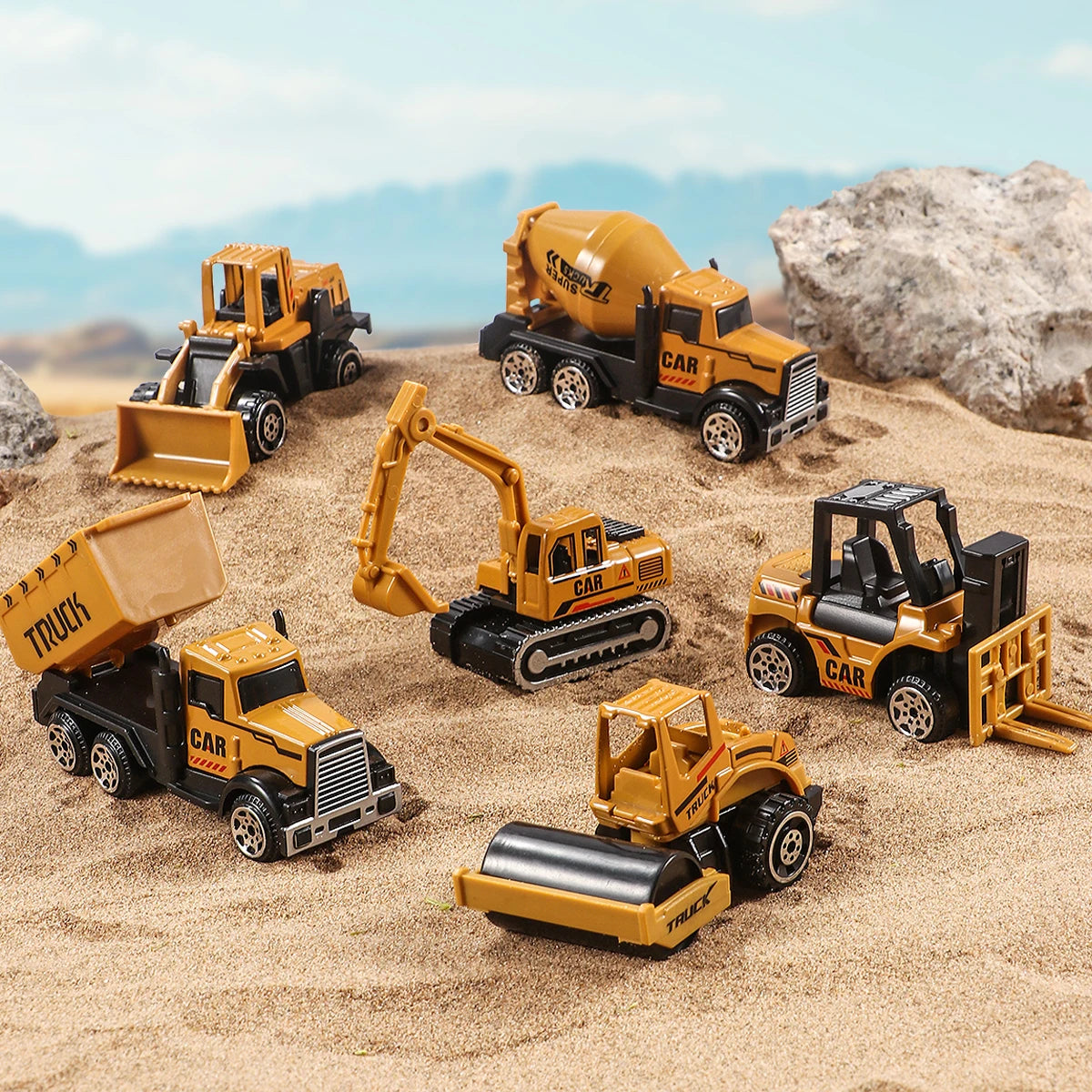 A set of diecast construction vehicles including a yellow tractor, excavator, and truck toy resting on sand.