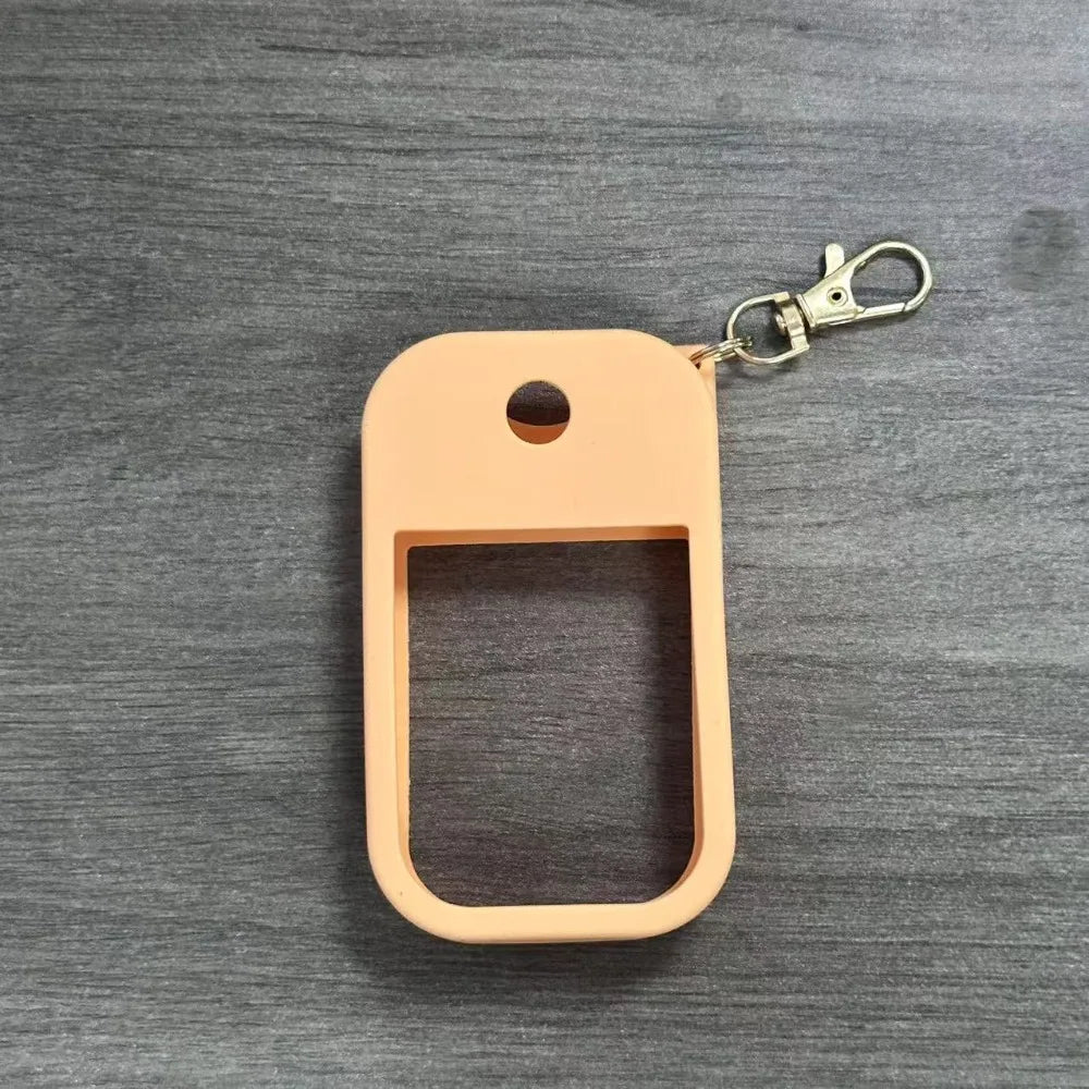 A light peach silicone protective case for a hand sanitizer spray attached to a metal keyring.