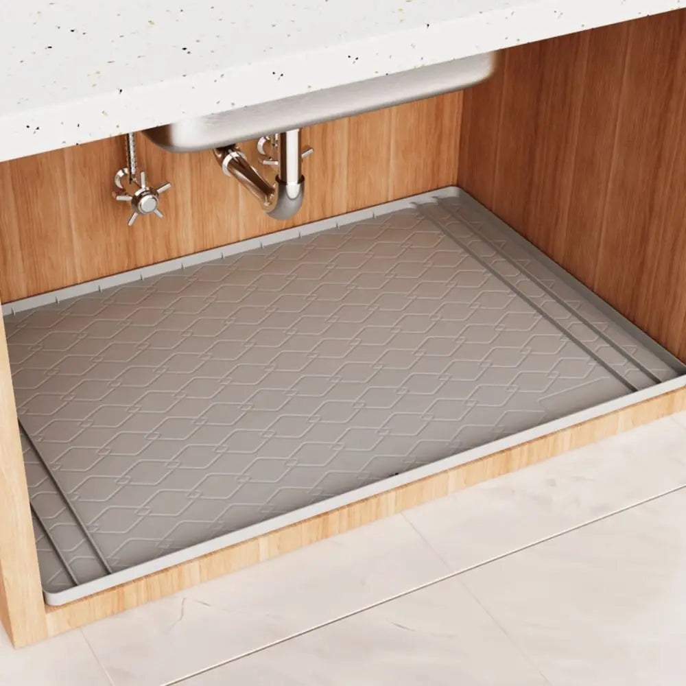 A silicone mat is placed inside an under sink cabinet to protect the surface.