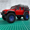 Red RC crawler vehicle with black roof rack and large mud terrain wheels on a green grid surface.