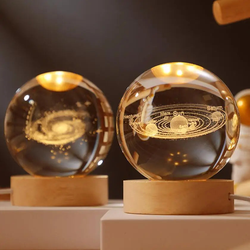A laser engraved crystal ball night light with a golden glow resting on a wooden base.