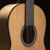 Close-up of the soundhole and fretboard of a classical guitar with silver-plated nylon strings.