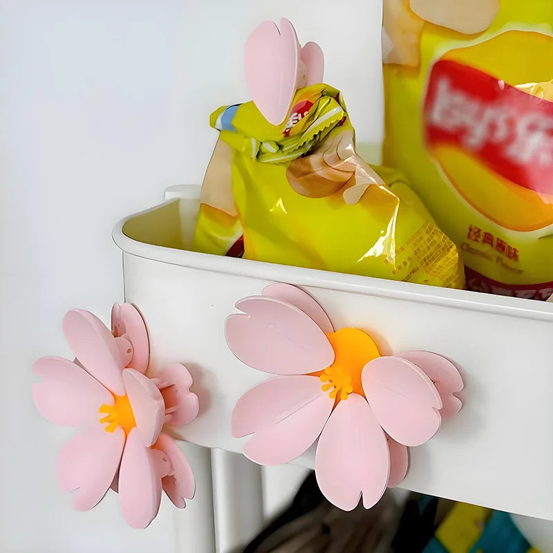 A yellow plastic bag sealed with a pink sakura flower magnetic clip on a white tray.