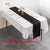 Elegant black satin table runner on a white tablecloth set for an event.