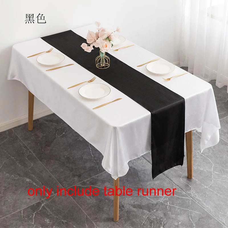 Elegant black satin table runner on a white tablecloth set for an event.