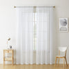 Sheer white voile curtains in two panels hanging from a rod pocket over a window.