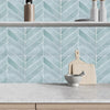 A kitchen backsplash featuring light blue geometric tiles and a wooden countertop with a bowl.