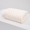 A roll of white plush coral velvet bath towels stacked horizontally on a white surface.