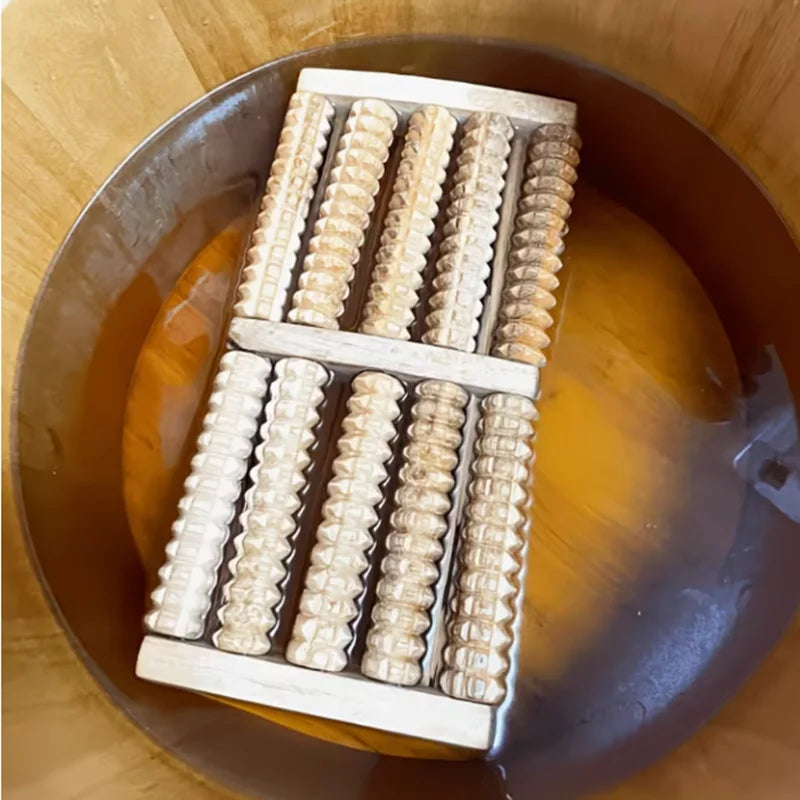 A wooden foot massage roller is placed in a brown bowl, showing its textured surface.