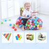 A large pile of colorful soft play balls in various shades of blue, green, and pink, with a toddler standing nearby.