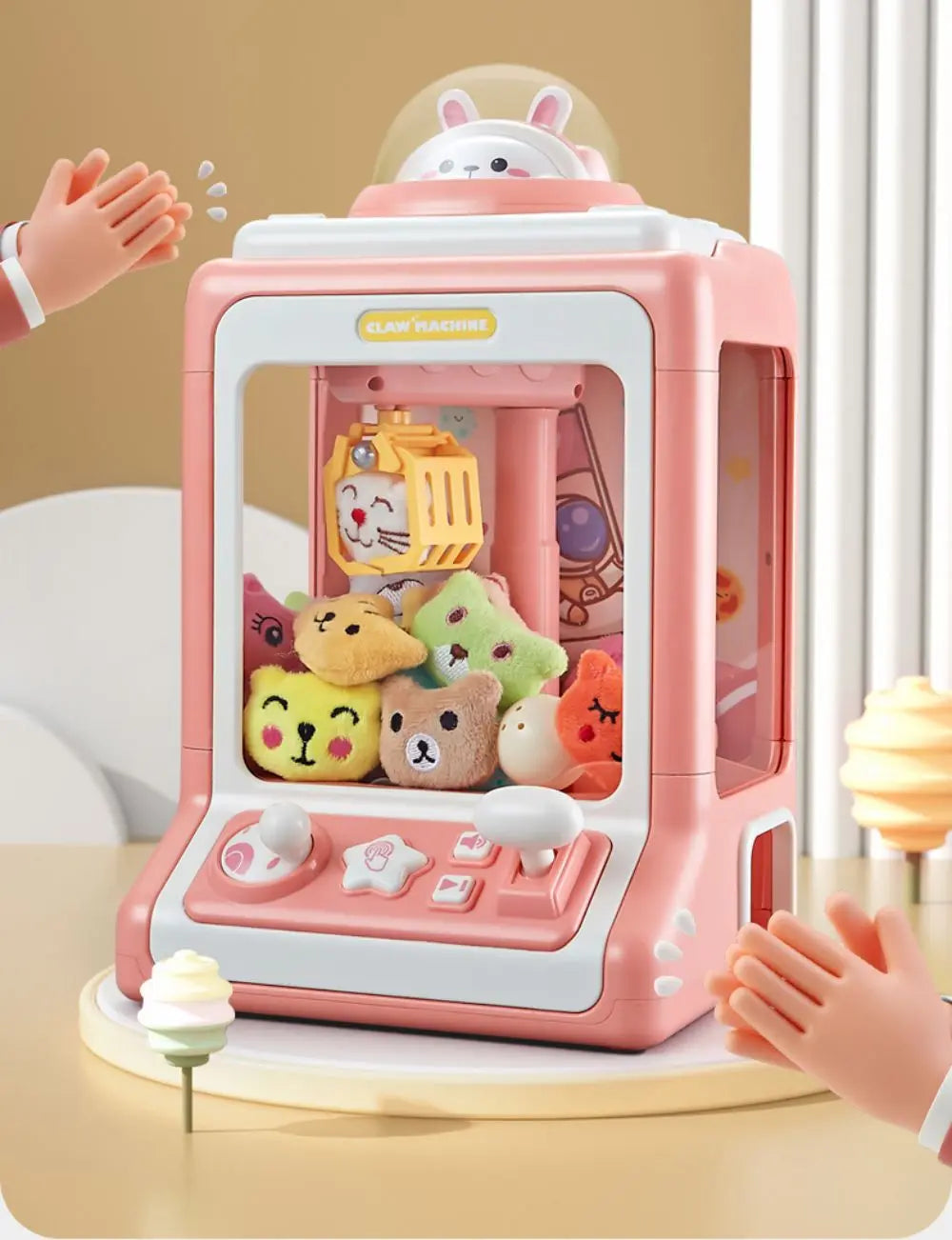 A pink mini claw crane machine for kids with lights and music is shown on a table.