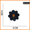A black embroidered iron-on patch shaped like a flower with an orange center.