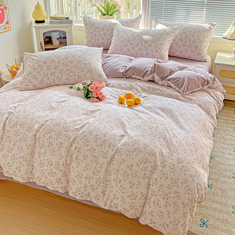 A pink floral duvet cover set with a matching flat sheet and pillows displayed on a bed.