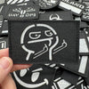 A close-up view of black tactical patches with white graphics and hook and loop backing