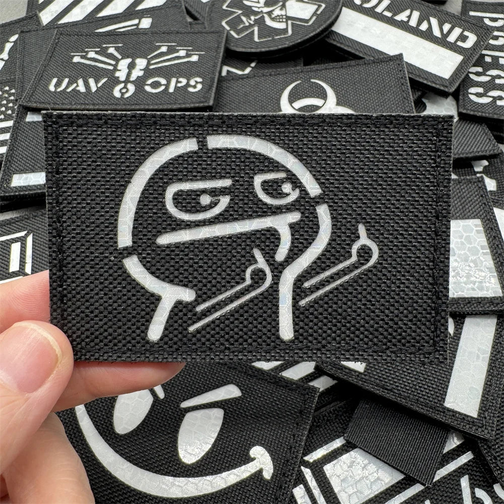 A close-up view of black tactical patches with white graphics and hook and loop backing