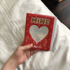 A red mini photo album with a heart-shaped clear window and text that reads I LIKE IT
