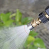 Close-up of a stainless steel high-pressure washer nozzle with a 1/4 quick connect fitting spraying a fine stream of water.