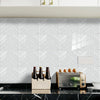 White herringbone marble peel-and-stick wall tiles displayed above a black countertop.