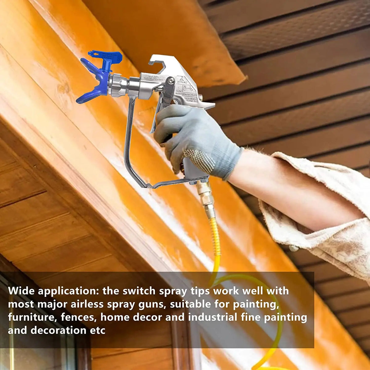 A hand wearing a glove is using a silver spray nozzle on a yellow wooden surface for painting or decoration.