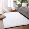 A fluffy white rug with a natural fiber border is placed on a wooden floor next to a gray sofa.