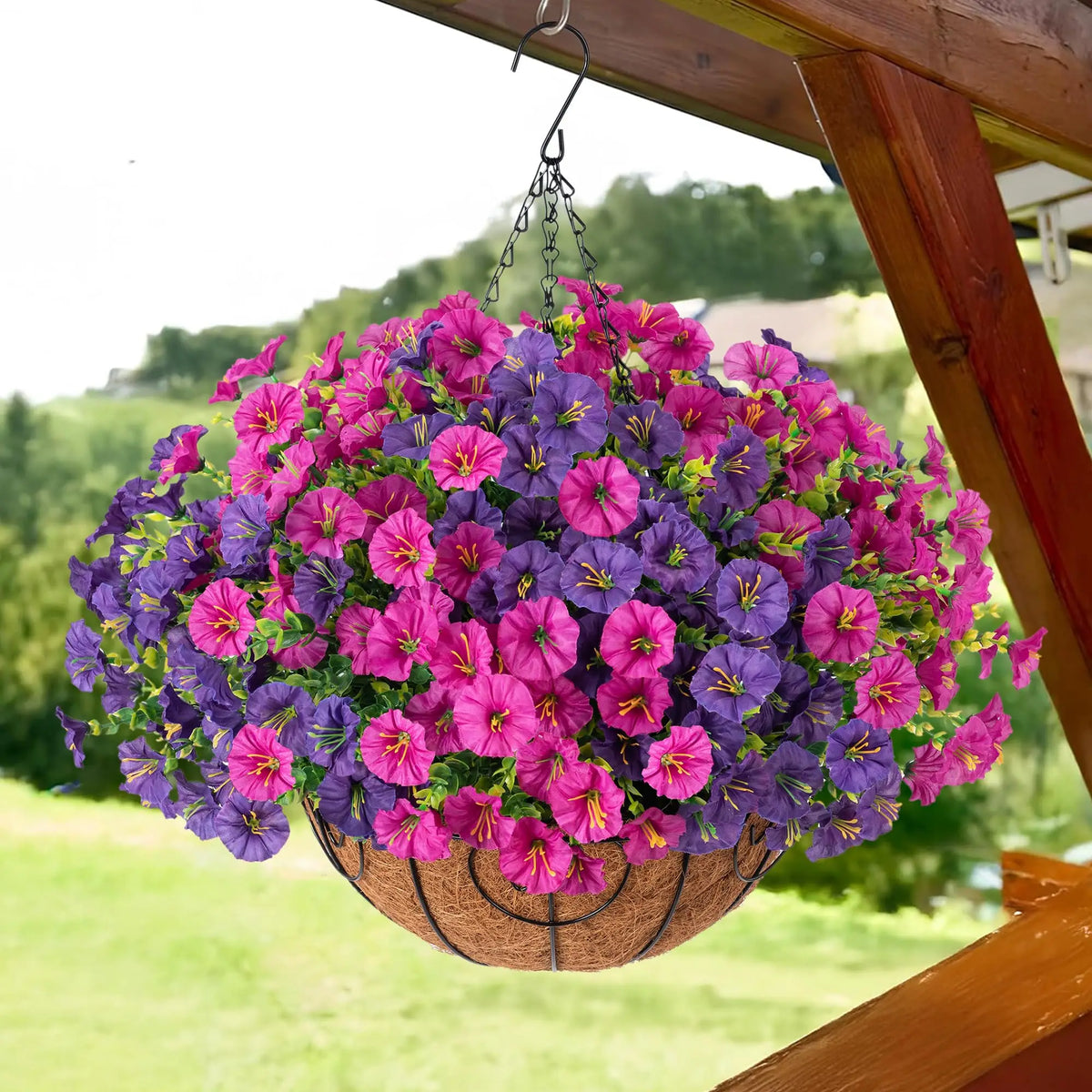A hanging basket filled with vibrant purple and pink artificial morning glory flowers, suspended from a wooden structure.
