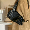 A woman wearing a tan jacket carries a black soft PU leather shoulder bag with silver rivet accents.
