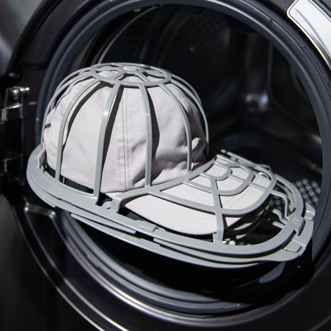 A gray cap protector cage is placed inside the drum of a washing machine.
