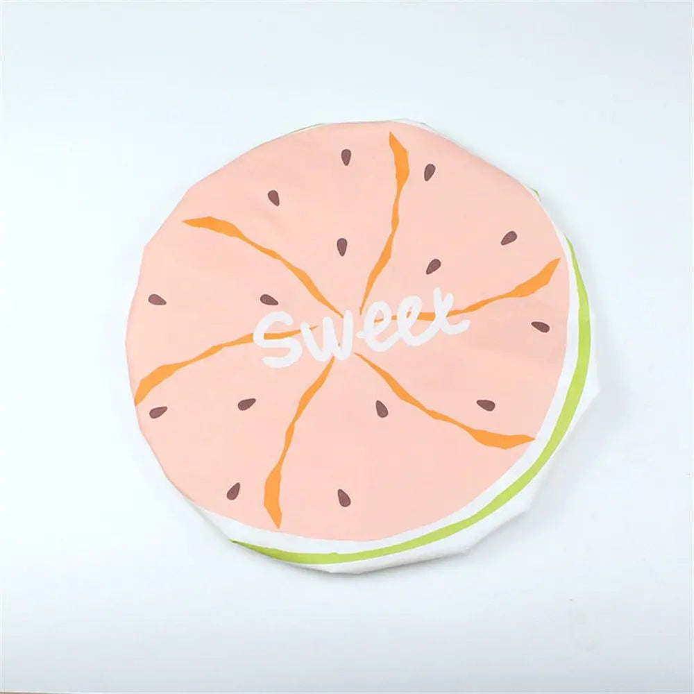 A pink fruit design on a waterproof shower cap featuring orange slices and the word sweet