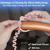 Hands are attaching a silicone safety strap to a baby's pacifier clip on a dark fabric.