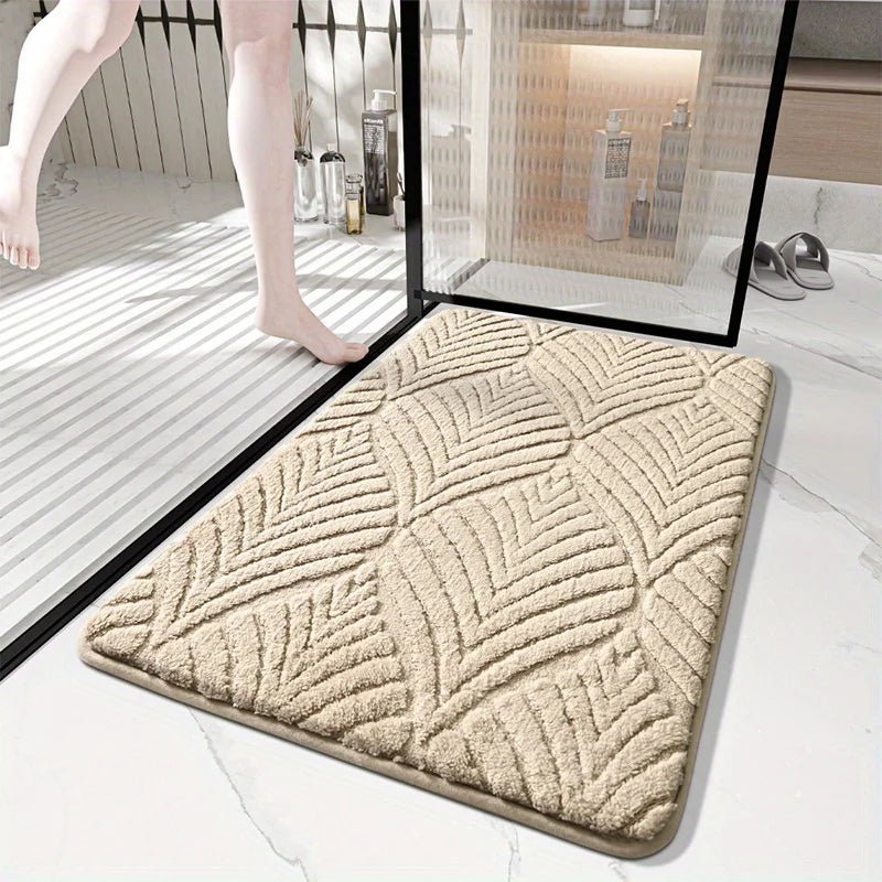 A beige plush velvet bathroom mat with a textured pattern is shown on a white marble floor.
