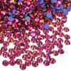 A close-up view of various hotfix rhinestones in shades of pink, purple, and orange scattered on a white background.