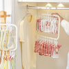 A white laundry drying rack with multiple clips holding pink and white baby clothes on a hanger.