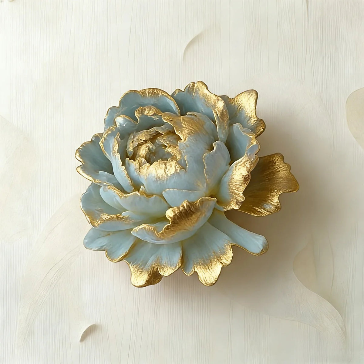 Un moule en silicone bleu clair en forme de rose avec des accents dorés, posé sur une surface blanche.