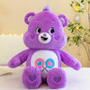 Peluche Kawaii Care Bears arcoíris morado con detalles rosa sobre una superficie blanca.