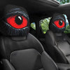 A pair of black car headrest covers featuring realistic, striking red eyes are shown inside a vehicle interior.