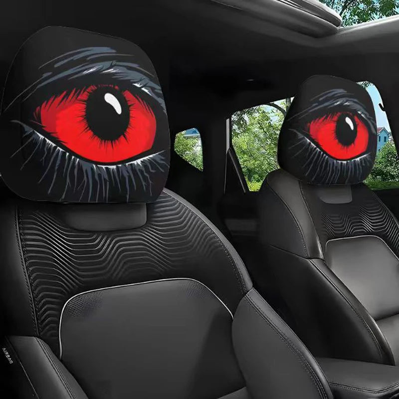 A pair of black car headrest covers featuring realistic, striking red eyes are shown inside a vehicle interior.