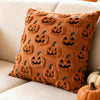 A brown plush throw pillow covered in an all-over pattern of carved jack-o'-lantern faces.