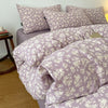 A close-up of a lavender printed duvet cover set with matching pillowcases on a bed.