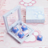 A clear plastic case holds silicone cat paw keycaps in blue and purple colors on a pink background.