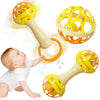 A baby is interacting with a yellow and orange sensory spinning rattle toy set.