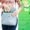A hand holds a light blue disposable toilet seat cover bag with green packaging and a floral shirt.