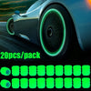 A set of twenty luminous green glow-in-the-dark tire valve caps displayed next to a modern car wheel.