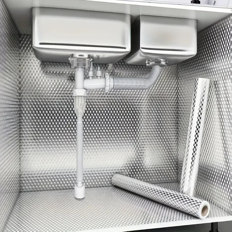 A close-up view of a self-adhesive aluminum foil wallpaper liner installed as a kitchen backsplash in a cabinet.