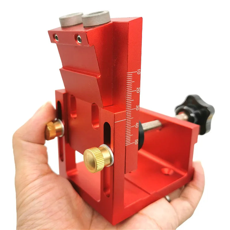 A red adjustable pocket hole jig kit is held in a hand, showing the wooden and metal components.