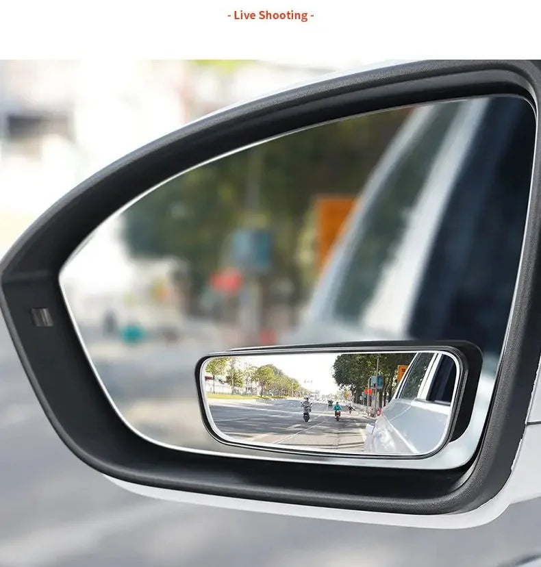 A close-up view of a car's side mirror showing a reflection of a street and surrounding environment.