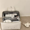 A white cosmetic storage bag with a gray lining and a clear top, featuring Miffy cartoon rabbit accessories.