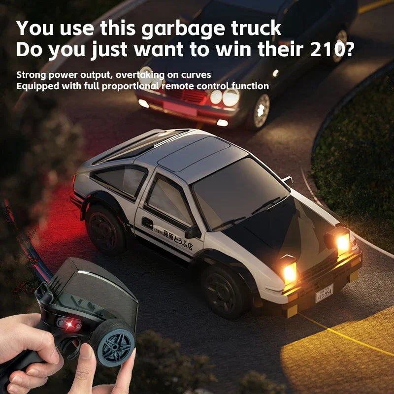 A hand holds a black remote control for a compact 1/64 scale 4WD RC drift car on an asphalt road.