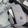 A gray water-resistant nylon chest sling bag with a black strap and a white interior lining is shown next to denim clothing.