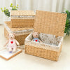 A stack of handwoven rattan storage baskets, some open revealing interiors with decorative paper, and a single basket lying o